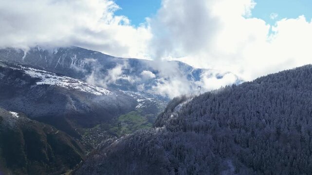 Aerial view of Tarentaise Valley with highway, alpine villages and snowy mountains covered in fog in the French Alps, Savoie, France.