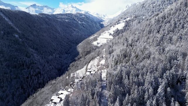 Aerial view of snowy Tarentaise Valley in the French Alps with fog, pine forests and dramatic winter mountains in Savoie, France.