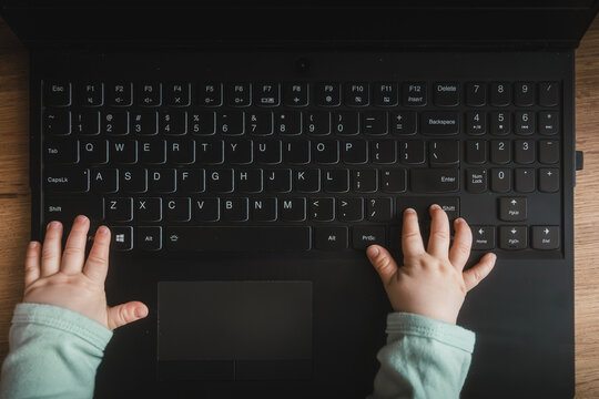 kontakt dziecka z technologią, małe rączki niemowlaka naciskają na klawisze laptopa