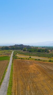 Vertical video. Balat, Turkey. Aerial drone flight over fields approaching ancient city of Miletus, view of the well-preserved ancient Greek Theatre on a sunny day. Aerial View. Rich colors