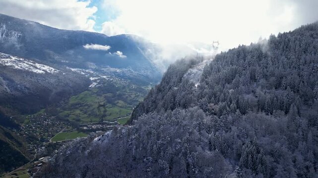 Aerial view of Tarentaise Valley with highway, alpine villages and snowy mountains covered in fog in the French Alps, Savoie, France.