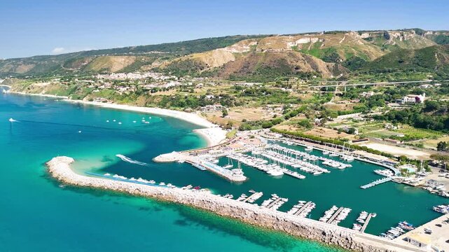 Breathtaking aerial view of Tropea's charming port, showcasing colorful fishing boats and elegant yachts moored in the calm turquoise waters of the Tyrrhenian Sea