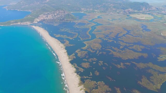 Dalyan, Turkey. Aerial drone view of Iztuzu Turtle Beach where Dalyan River meets Mediterranean Sea, showing golden sand spit, channels and waves.. Aerial View