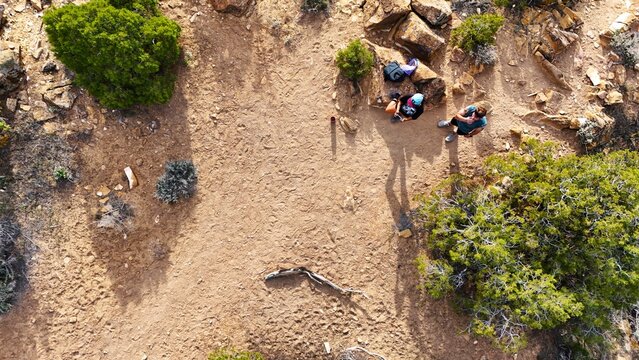 Aerial view of hikers resting in the arid landscape, the ochre earth contrasting with the deep green shrubbery, Palisade, Colorado, USA.