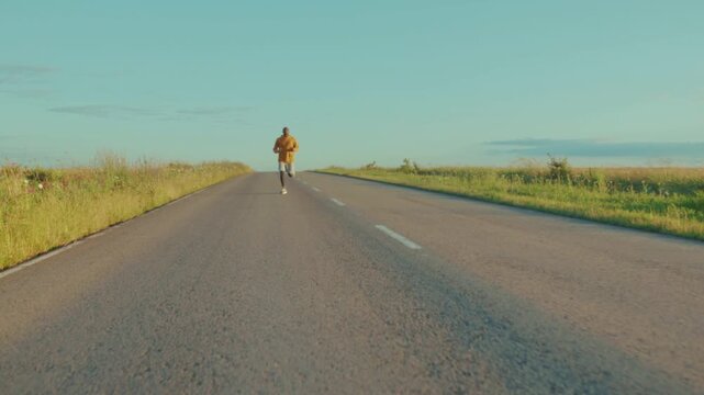 Solitary runner stretches toward horizon, Isolated figure advances along deserted asphalt during sunset light