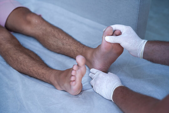 Doctor examining patient feet in clinic. Close-up of podiatry check, foot care, diagnosis and treatment concept, healthcare professional wearing gloves during medical examination.