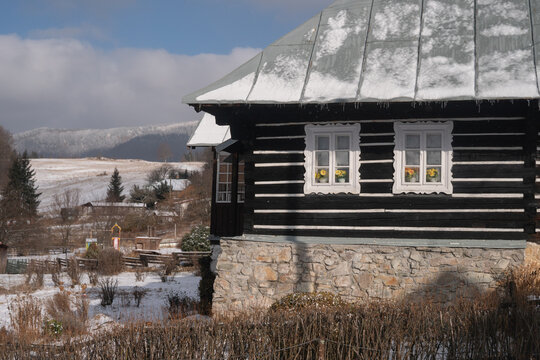 View of a traditional dark wooden house with snow-dusted roof and intricate window frames, nestled in a snowy landscape, Donovaly, Banskobystricky kraj, Slovakia.