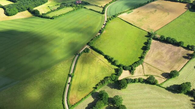 Drone shot of patchwork farmland and lush fields near Cuncy les Varzy, France, showcasing rural countryside and agricultural landscape.