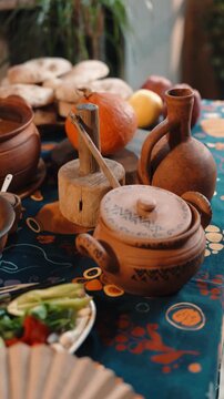 Traditional Georgian supra table set with clay dishes and a rich variety of food. Rustic textures, authentic tableware, and warm atmosphere showcase Georgian hospitality