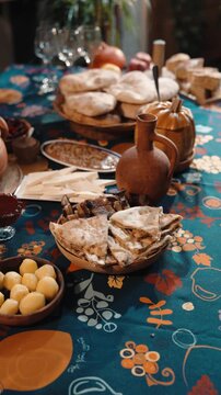 Traditional Georgian supra table set with clay dishes and a rich variety of food. Rustic textures, authentic tableware, and warm atmosphere showcase Georgian hospitality
