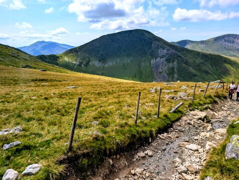 Hikers walking on mountain trail beside wire fence outdoor recreation