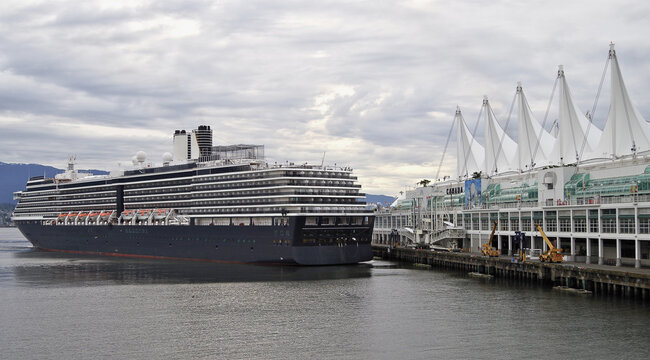 Modern luxury cruiseship cruise ship liner Oosterdam returning to Vancouver, BC Canada from Alaska cruise during early morning grey misty rainy foggy day silhouette harbor landscape marine traffic