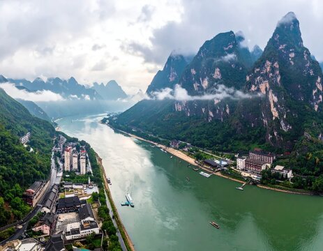 An aerial view showcases a winding river flowing through a stunning landscape of karst mountains and lush greenery.