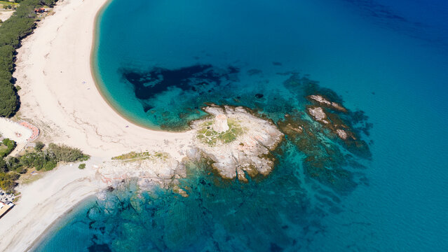 Aerial drone view of Torre di Bari, surrounded by turquoise waters and white sandy beaches along the eastern coast of Sardinia on a clear sunny day