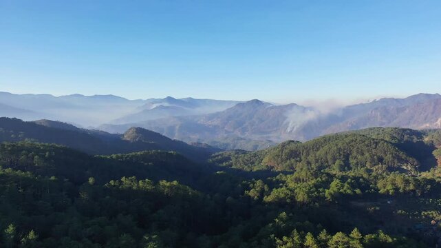 Aerial view of lush green mountains and misty valleys near Bontoc and Sagada in the Philippines under a clear blue sky.