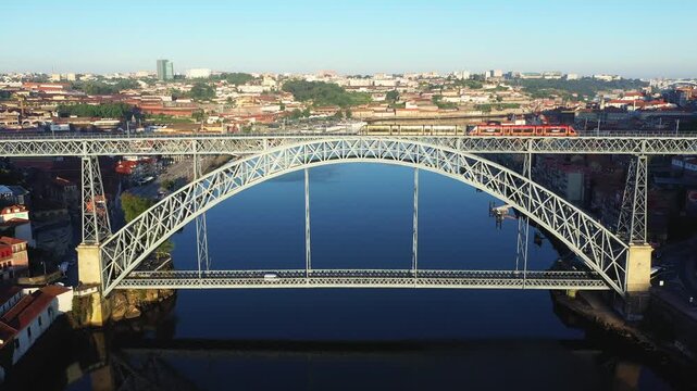 Aerial view of the iconic Dom Luis I Bridge spanning the Douro River in Porto, Portugal, with the cityscape in the background on a clear day.