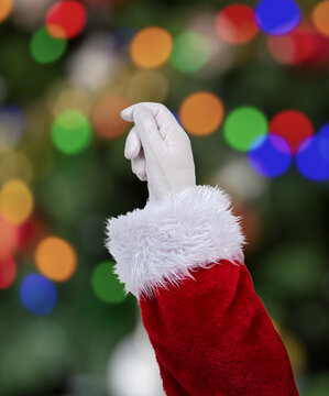 Shot of an Santa Claus hand pulling something at home with christmas tree