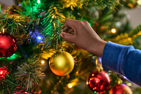 Kid, hand and christmas tree with bauble for decor, festive event or december holiday in home. Closeup, ornament or hanging sparkle ball for new year celebration or Santa decorations at house