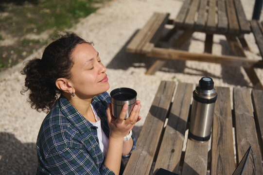 Woman enjoying coffee with closed eyes outdoors, peaceful moment