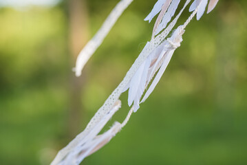 Large white dream catcher hanging from a rustic wooden teepee frame in a sunlit forest  © Stephan