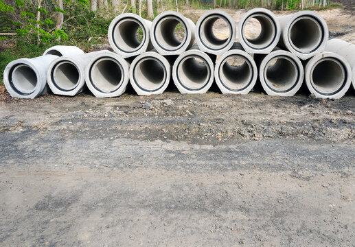 Blick auf eine Baustelle mit gestapelten gro&szlig;en Betonrohren f&uuml;r den Einsatz bei Kanalarbeiten im Zuge einer Fahrbahnsanierung, extra viel Copy Sapce im Vordergrund