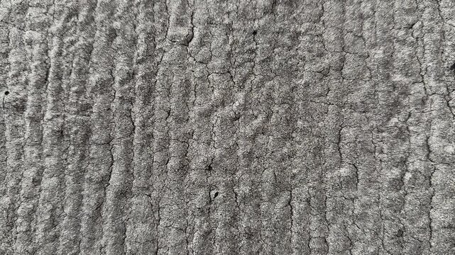 Uniflex waterproofing close-up granular asphalt texture, macro view of gray granule coated membrane with parallel trowel ridges.