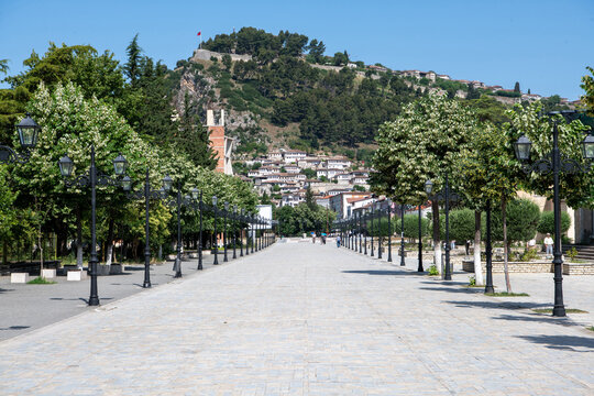 Bulevardi Republika treelined pedestrian zone with traditional white Ottoman houses in the distance on a summer day, Berat, Albania