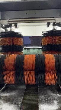View of a car removing dirt by rollers with soap and water during a car wash in an automatic tunnel. Car going through an automated car wash machine.