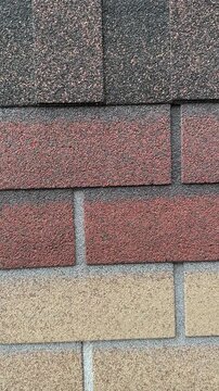 Close-up ondulin cottage roof shingles showing granular texture and mortar lines, weathered earthy tones, asphalt granules.
