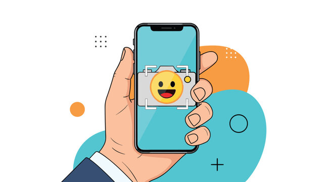 Hand holding a modern smartphone capturing a photo of a happy yellow emoji face through the camera interface with colorful background.
