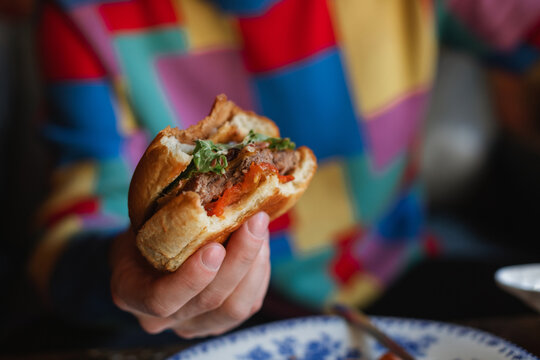 Close-up of a man sitting at a table holding a half eaten hamburger
