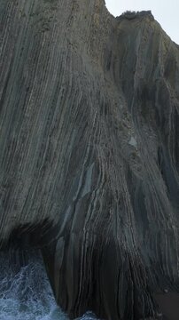 Close view of Flysch cliff with stone strata by the water in Zumaia