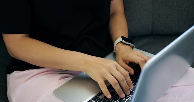 Focused Asian woman working on laptop late. Asian female programmer debugging scripts during night shift. Concentrated Asian woman developer writing and testing code late into night