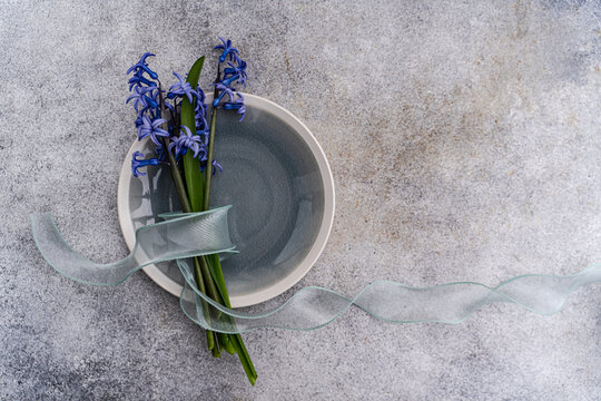 Overhead view of a bunch of fresh blue hyacinths tied with a ribbon on a ceramic plate on a table