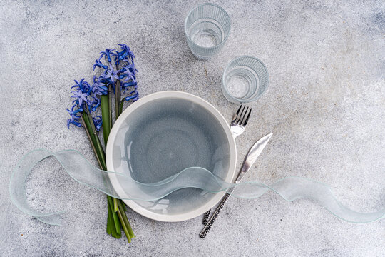 Overhead view of a spring place setting on a table with a bunch of fresh blue hyacinth flowers and a ribbon