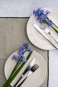 Overhead view of two rustic spring place settings with fresh blue hyacinths on a table