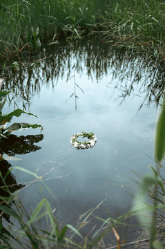 Floral wreath floating on rural pond at summer solstice