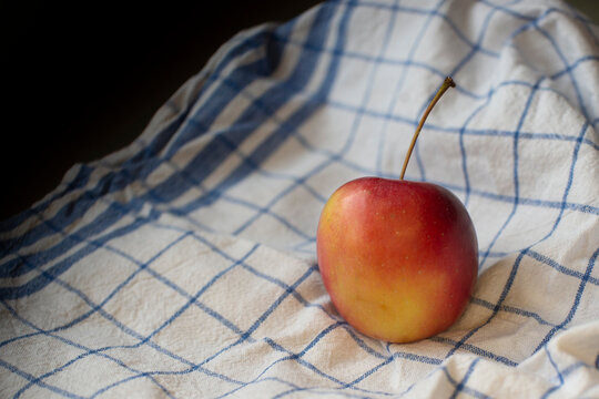 Close-up of a single apple on a checked tea towel