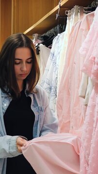 Buyer reviews fabric. Customer inspects dress details thoroughly. Woman closely examines fabric and fit carefully. Customer precisely checks seams and layers of pink gown in warm light