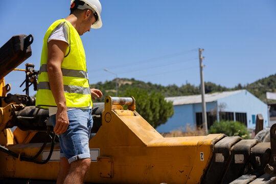 Male engineering worker inspecting heavy machinery on site