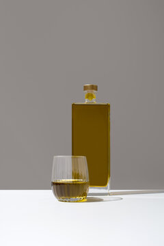 Minimal still life of olive oil bottle and tasting glass