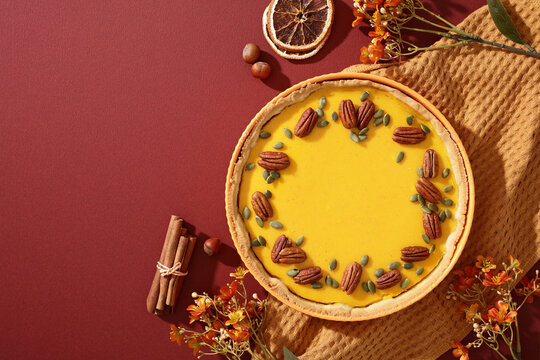 Autumn pumpkin pie with pecans, seeds and holiday decor