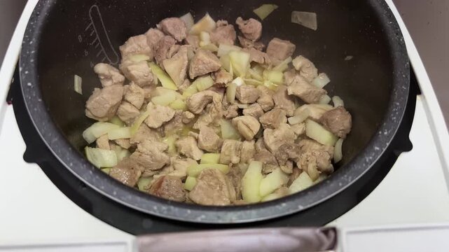 Meat with onion stewing in multi-cooker during goulash cooking