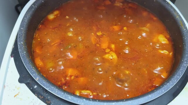 Boiling of goulash in multi-cooker pot during its cooking