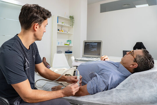 Physiotherapist performs arm ultrasound on patient in clinic