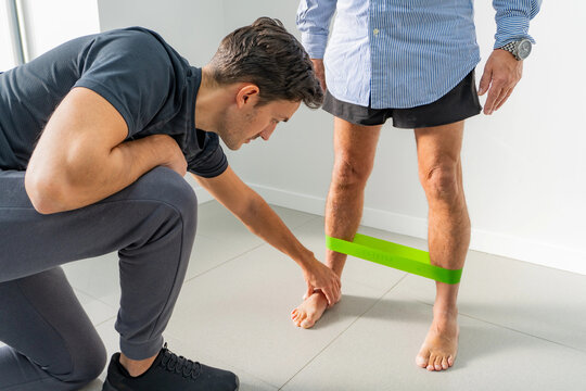 Physiotherapist assessing foot soles during band exercise
