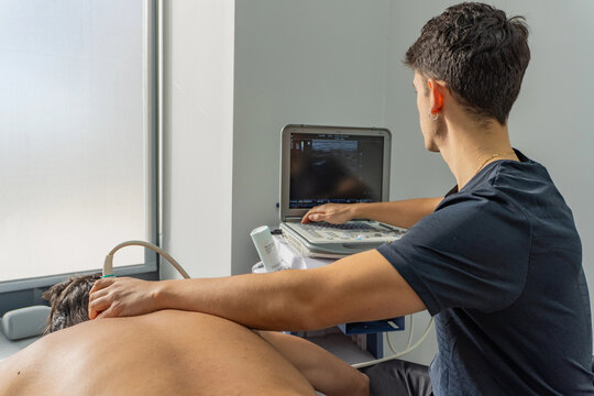 Physiotherapist using ultrasound on patient back in clinic