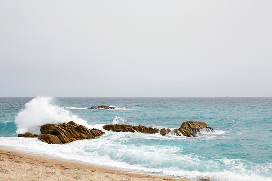 Rocky shore with crashing waves on a calm coastal sea