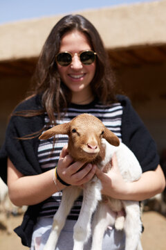 Tourist holding baby goat at farm in Morocco, north Africa
