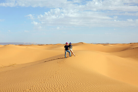 Travelers standing on sand dunes in Morocco Sahara desert